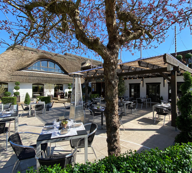 Thatched restaurant patio with chairs and dining tables